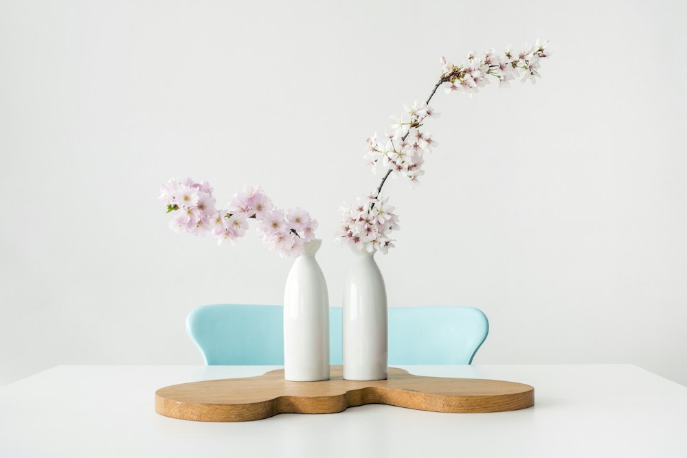 White ceramic vases holding spring blossoms on a wooden tray